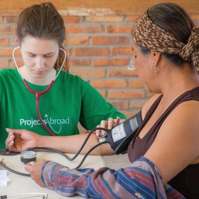 A volunteer performing a standard blood pressure test on a local woman A Projects Abroad volunteer at her Spring Break Public Health placement checking the blood pressure of a local woman